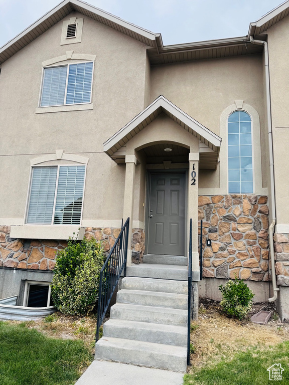 Doorway to property with stone siding and stucco siding