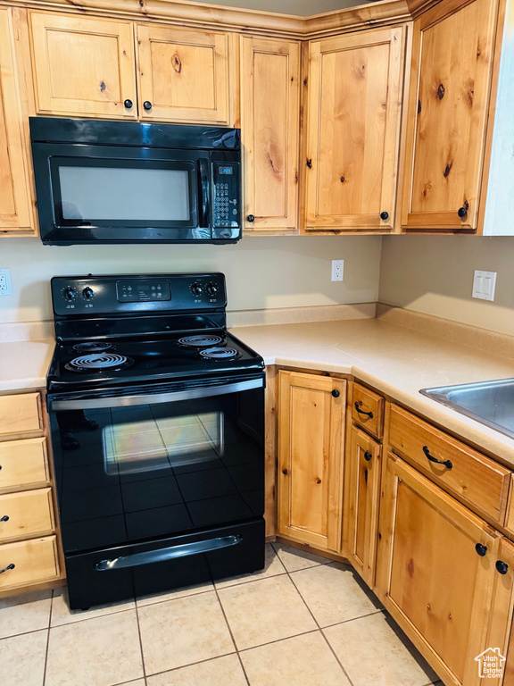 Kitchen with black appliances, light tile patterned floors, and light countertops
