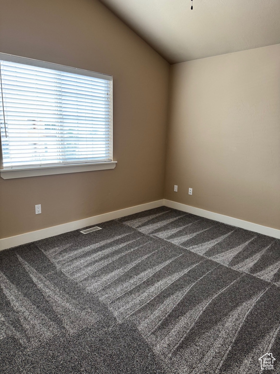 Spare room with vaulted ceiling and dark carpet