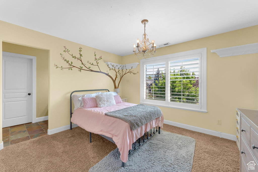 Carpeted bedroom featuring a chandelier and baseboards