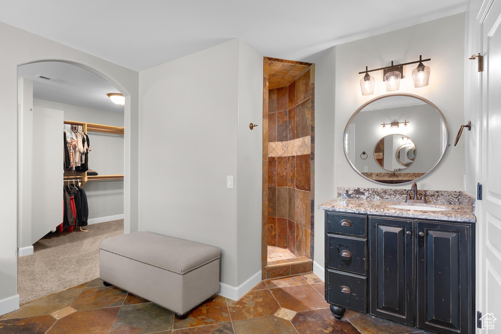 Bathroom with tiled shower, vanity, and a spacious closet