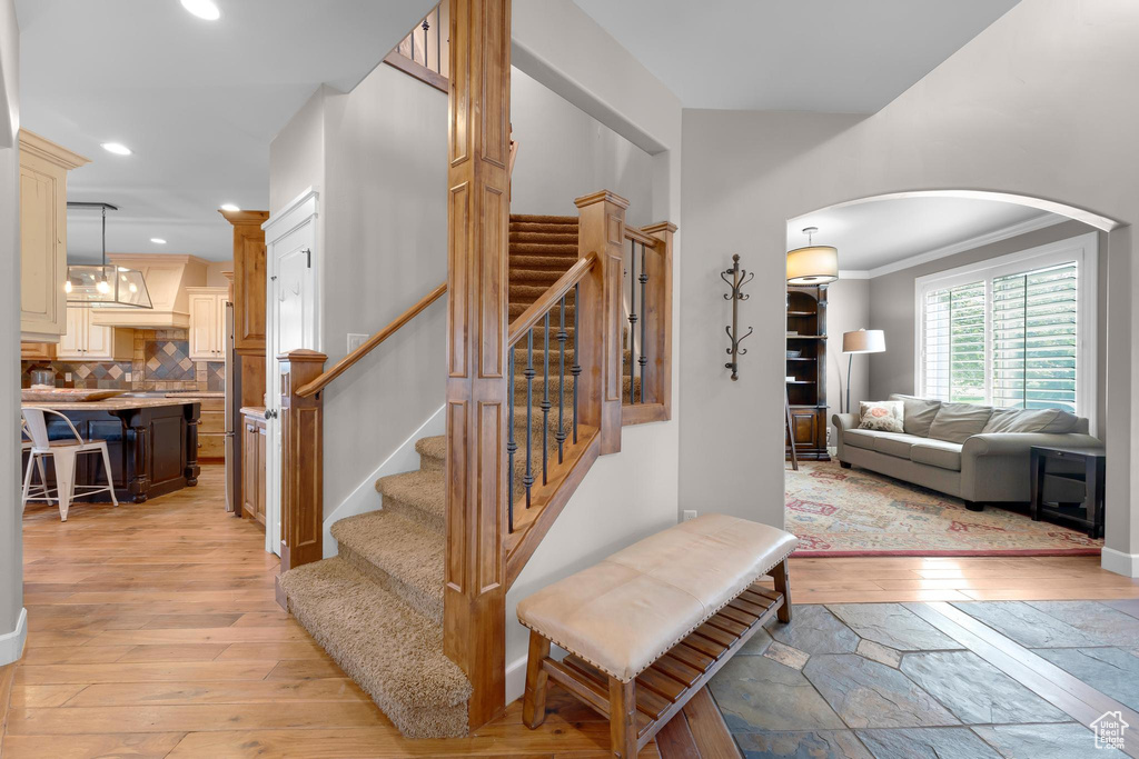 Stairway with wood-type flooring, arched walkways, recessed lighting, and ornamental molding