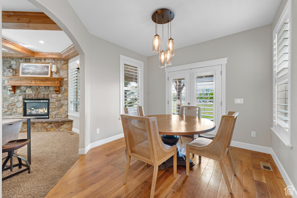 Dining room featuring light wood finished floors, a fireplace, french doors, and arched walkways