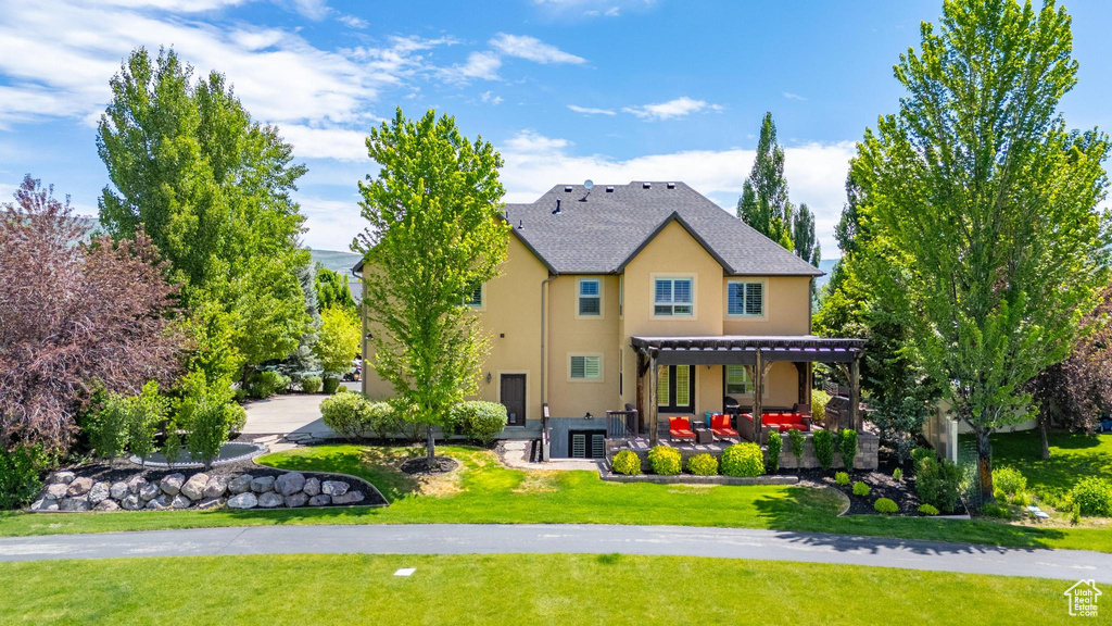 Rear view of property featuring stucco siding, a patio area, and a yard