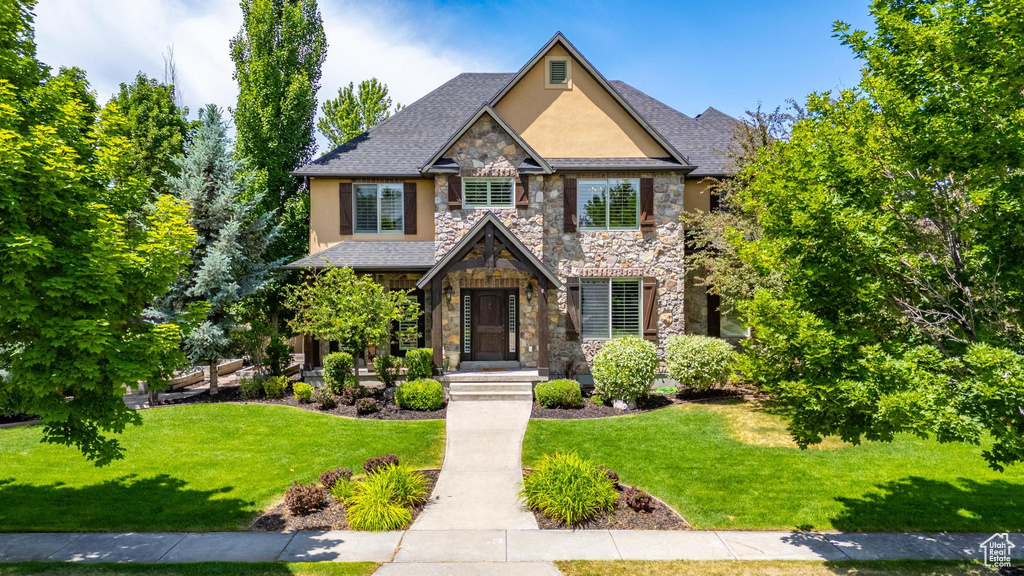 Craftsman house with stone siding, stucco siding, and a front yard