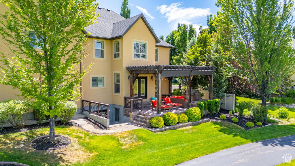 Back of property with a pergola, stucco siding, a patio, and a yard