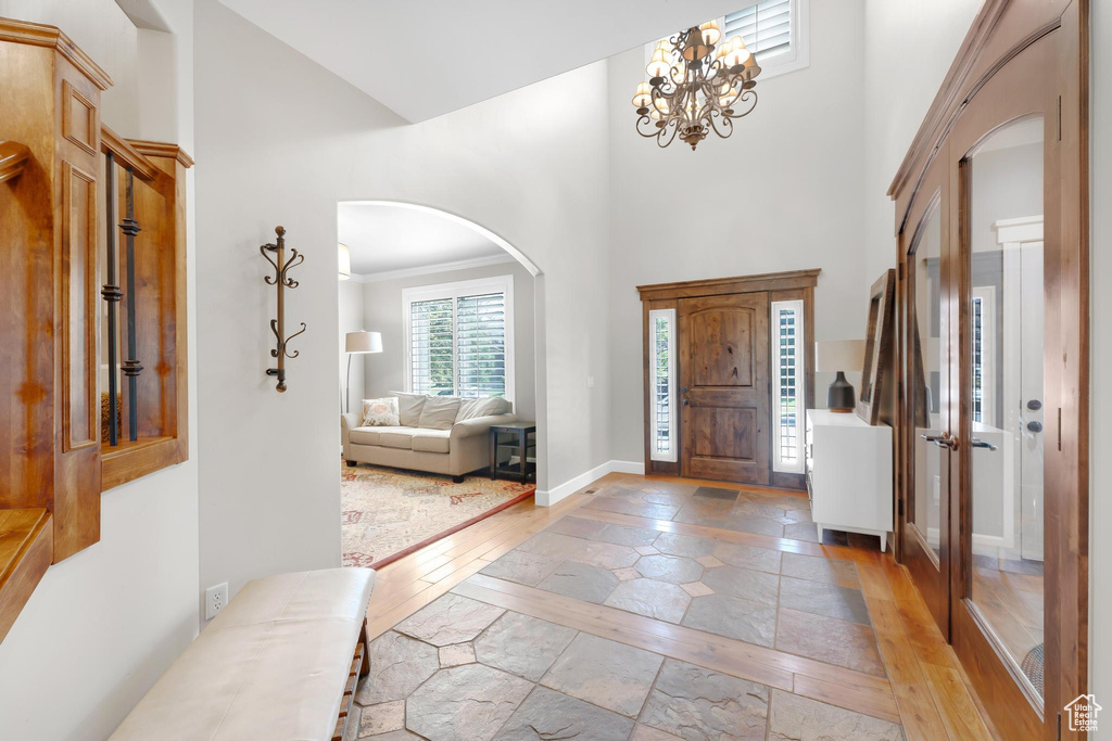 Foyer featuring inlaid floor details, arched walkways, a high ceiling, stone tile flooring, and a chandelier