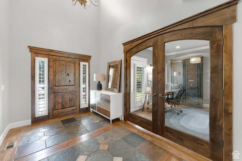 Entryway with stone tile floors, french doors, a high ceiling, and arched walkways