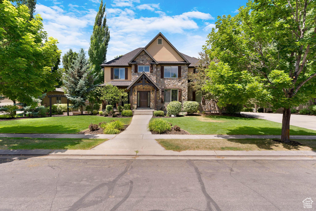 Craftsman-style home with stone siding and a front yard