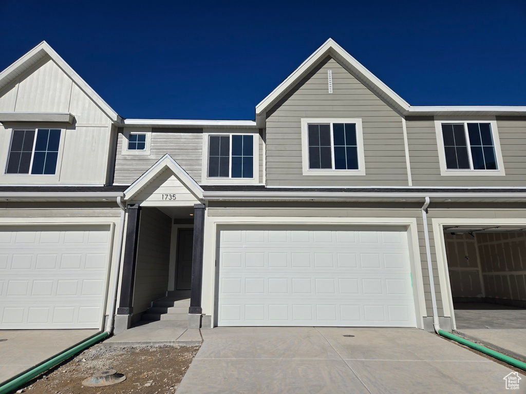 Townhome / multi-family property featuring an attached garage and concrete driveway