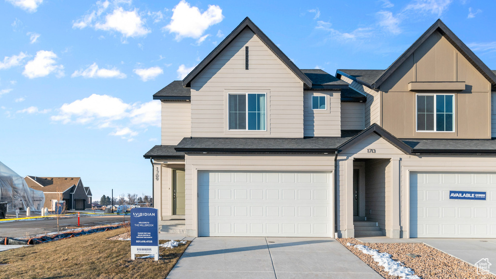 Townhome / multi-family property with an attached garage, driveway, and a shingled roof