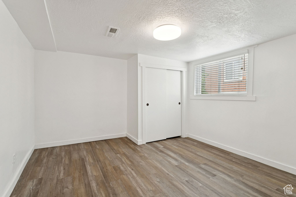 Unfurnished bedroom with wood finished floors, a textured ceiling, and a closet