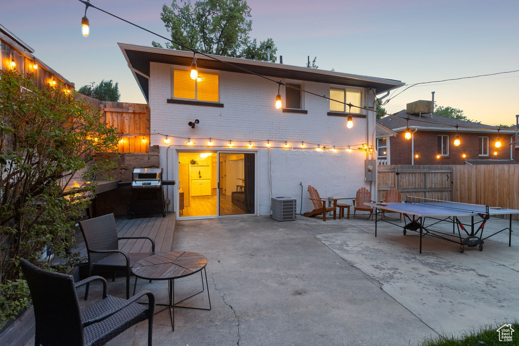 Back of house at dusk featuring a patio, a fenced backyard, and brick siding