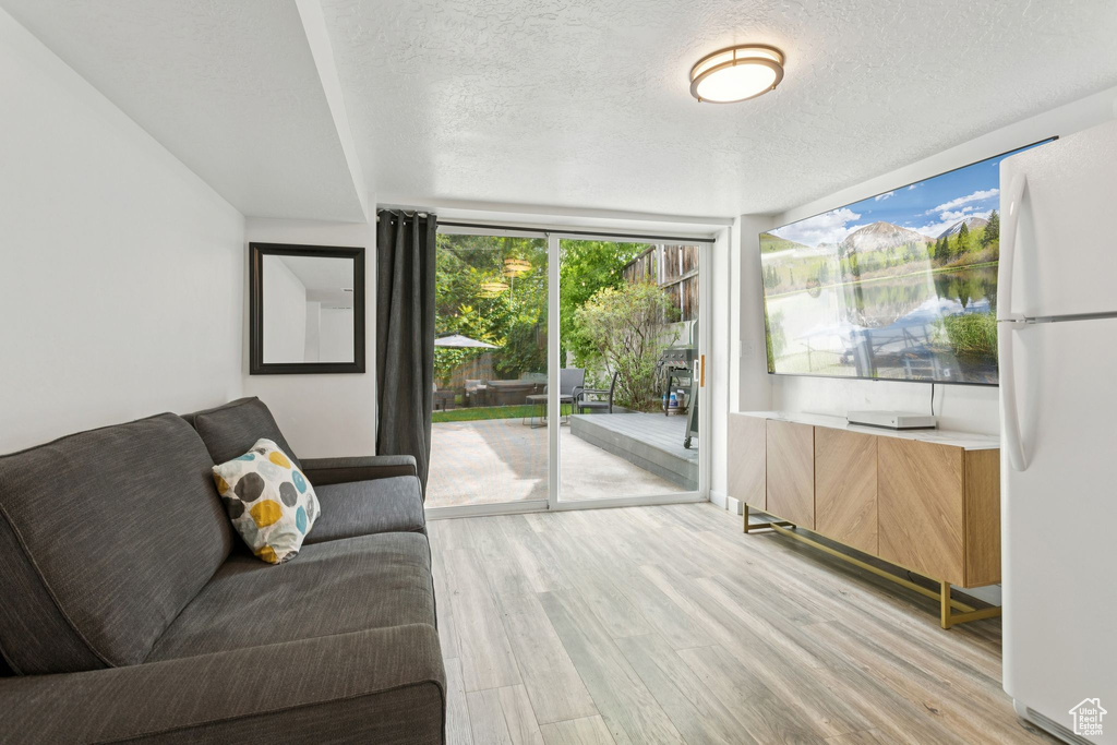 Living area featuring light wood finished floors, a textured ceiling, and expansive windows