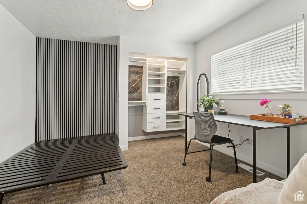 Carpeted office space with built in study area and baseboards