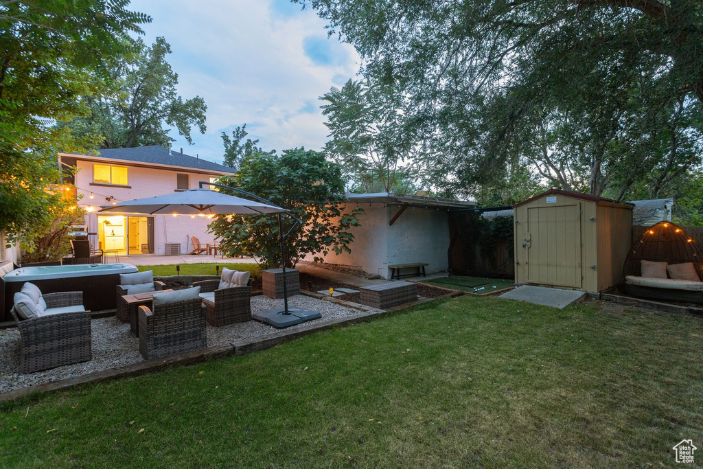 View of green lawn with a storage unit and a patio