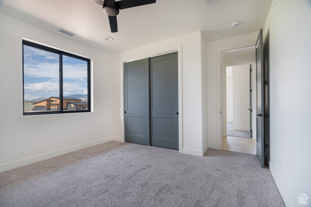 Unfurnished bedroom featuring carpet, a closet, and ceiling fan
