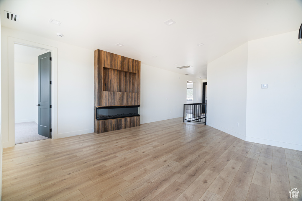 Unfurnished living room featuring light wood-style flooring and baseboards