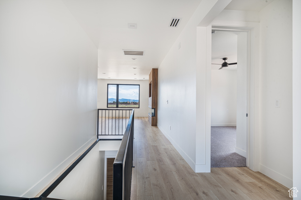 Hall with an upstairs landing and light wood-style flooring