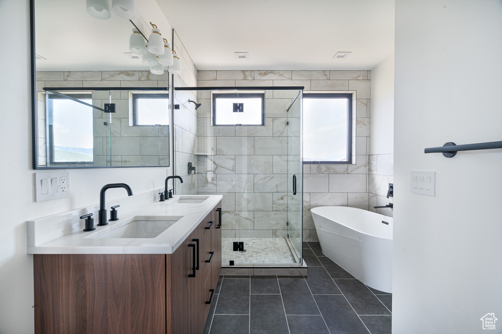 Full bath with healthy amount of natural light, double vanity, a soaking tub, a shower stall, and tile walls