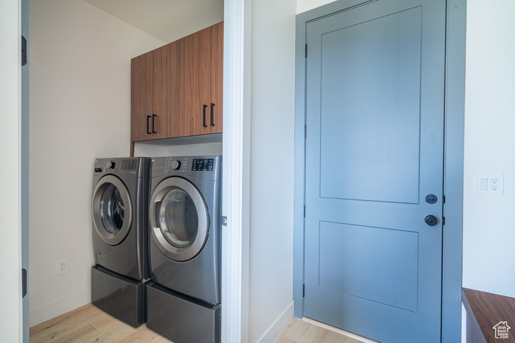 Laundry room with washer and clothes dryer, cabinet space, and light wood finished floors
