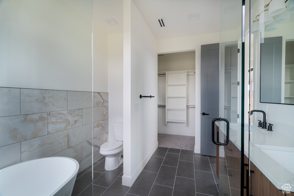 Bathroom featuring tile walls, vanity, a freestanding tub, a spacious closet, and tile patterned floors