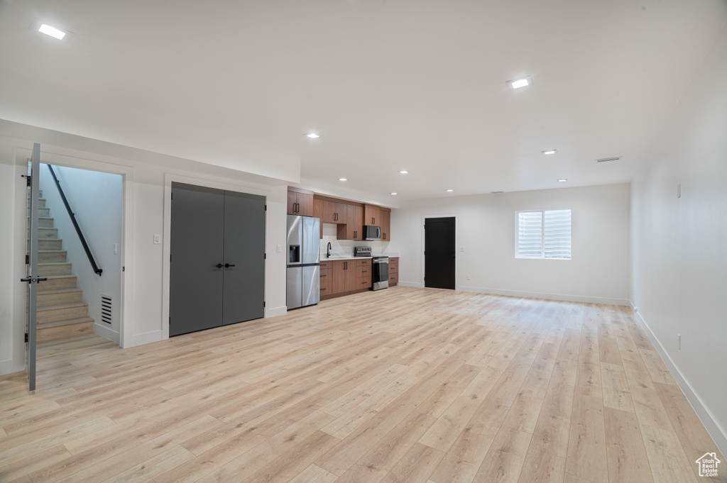 Unfurnished living room with light wood-style floors, stairs, and recessed lighting