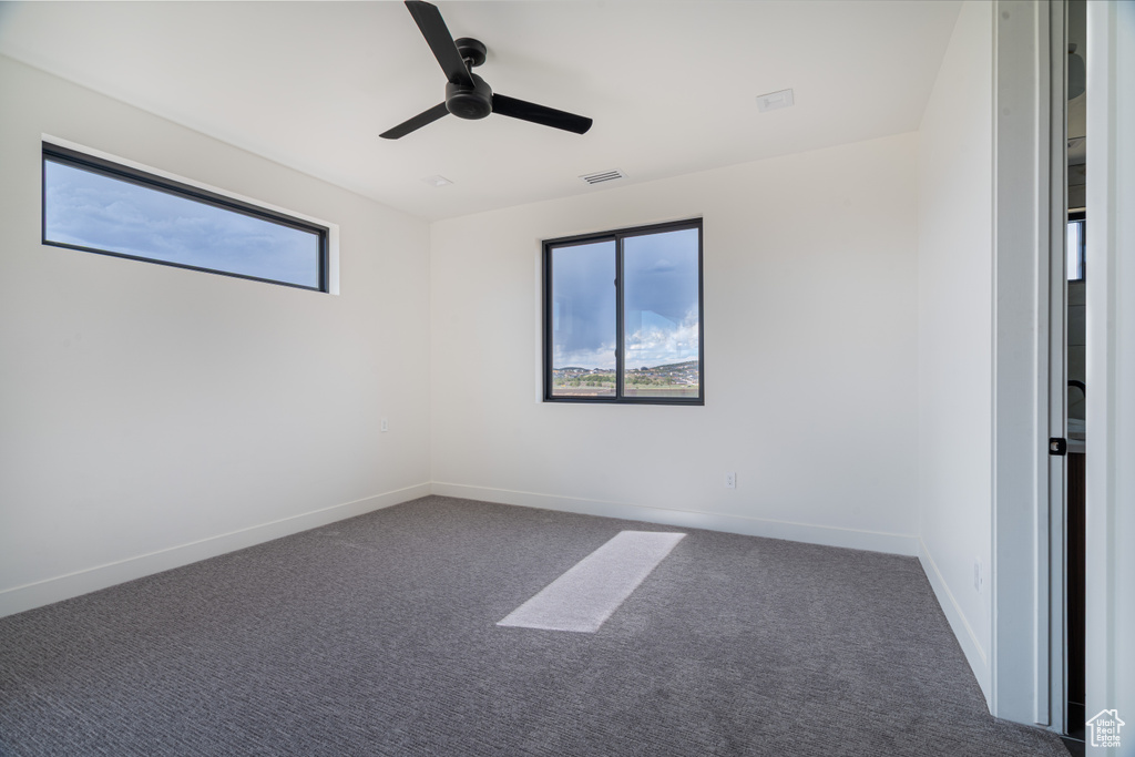 Carpeted empty room with ceiling fan and baseboards