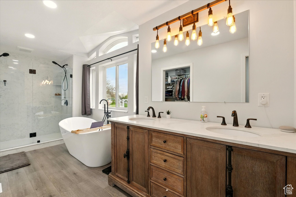 Full bathroom with a shower stall, a soaking tub, double vanity, wood finished floors, and recessed lighting