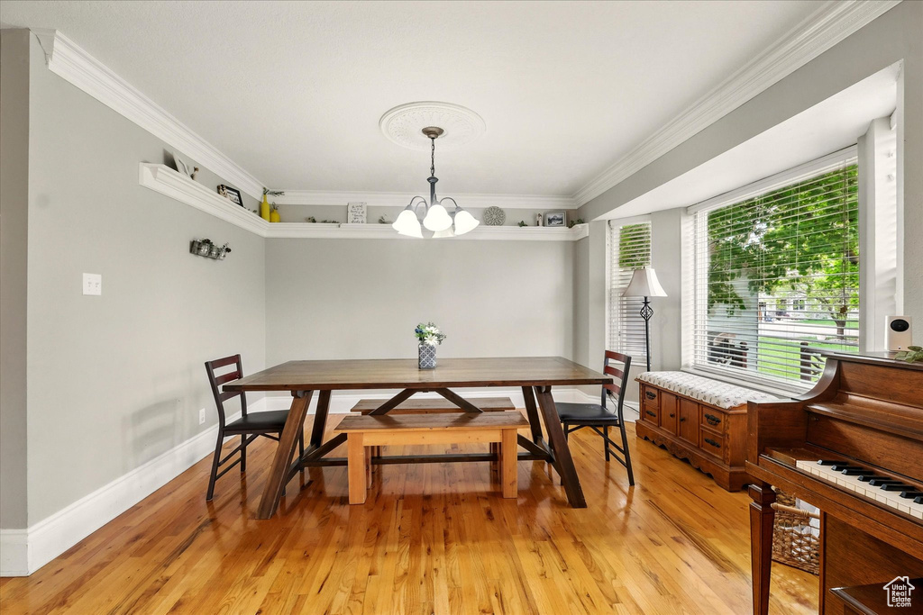 Dining room with a chandelier, light wood-style flooring, and crown molding