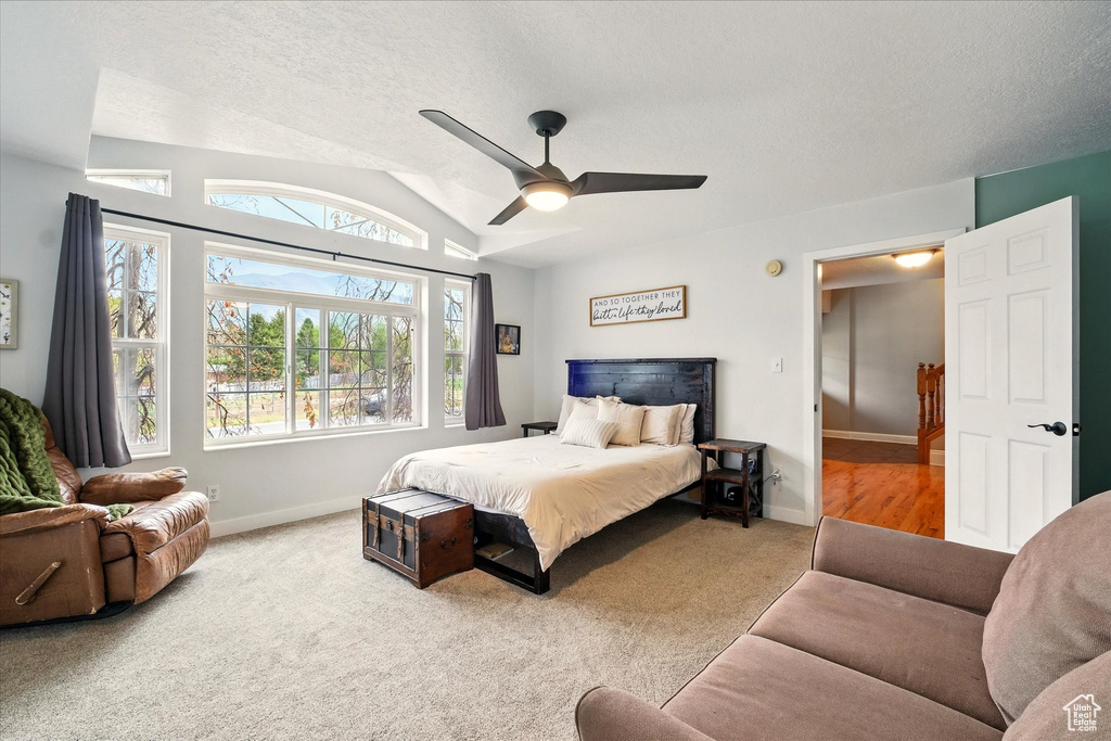 Bedroom with carpet flooring, vaulted ceiling, a textured ceiling, and ceiling fan
