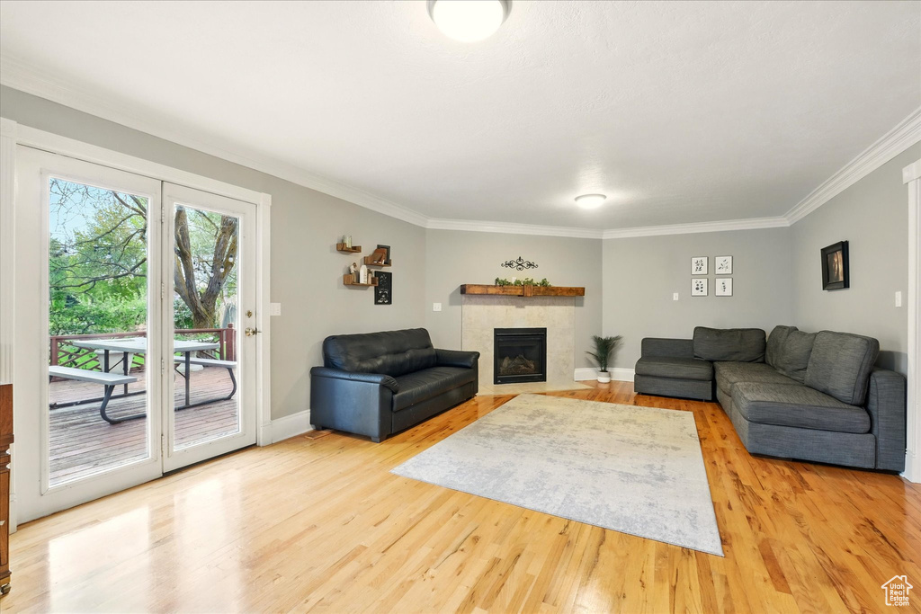 Living area with light wood-style floors, crown molding, and a tile fireplace