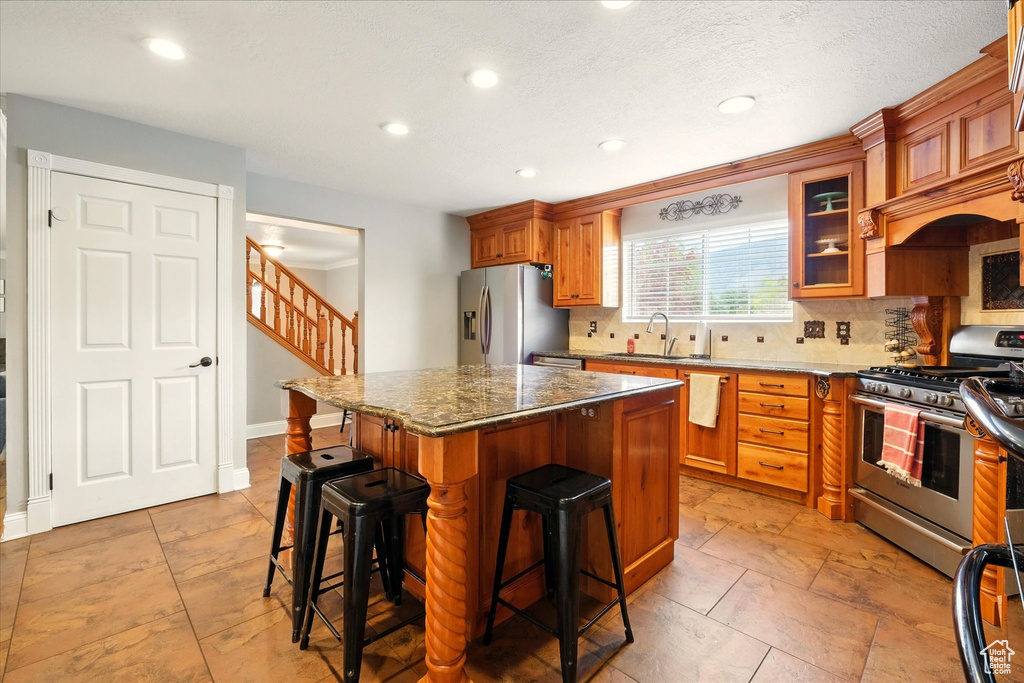 Kitchen with appliances with stainless steel finishes, a breakfast bar, tasteful backsplash, recessed lighting, and a center island