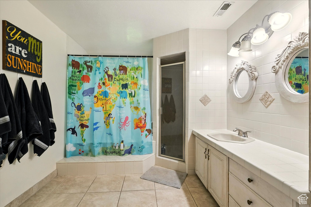 Bathroom with a stall shower, vanity, and tile patterned flooring