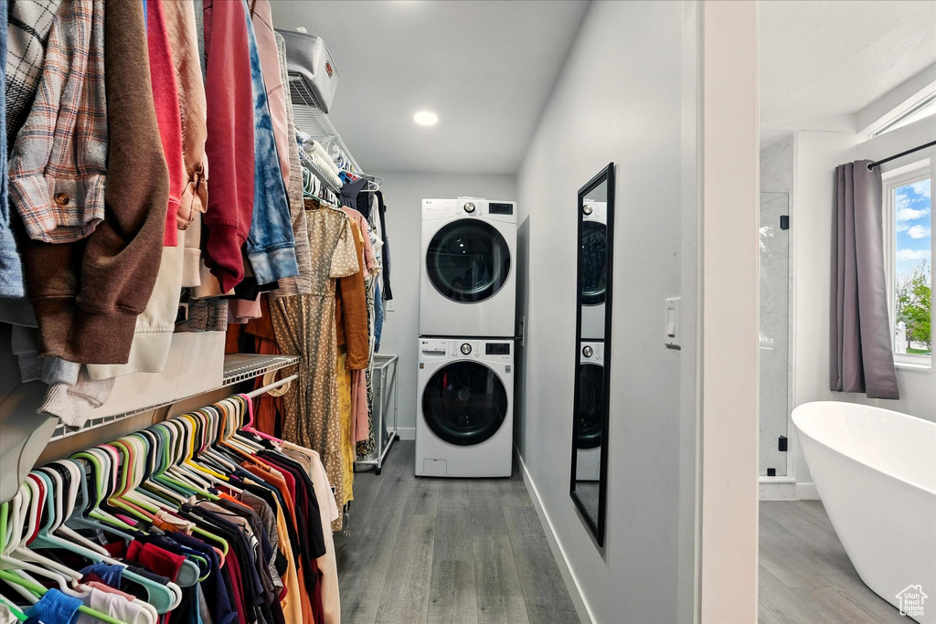 Laundry area with stacked washer / drying machine, wood finished floors, and recessed lighting