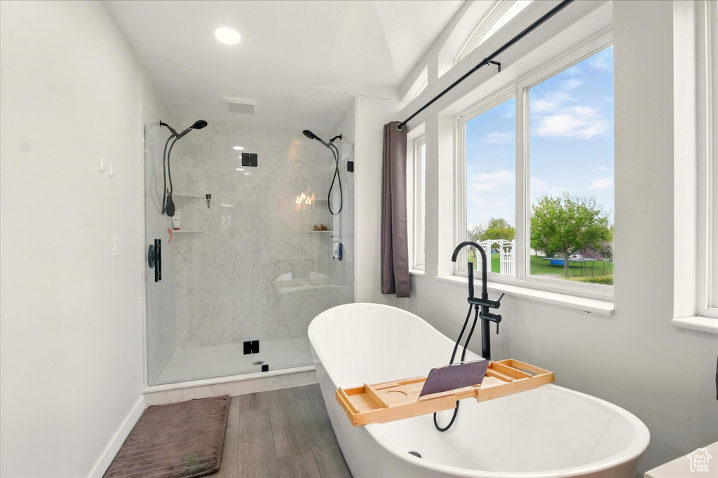 Bathroom featuring a marble finish shower, a soaking tub, and wood finished floors