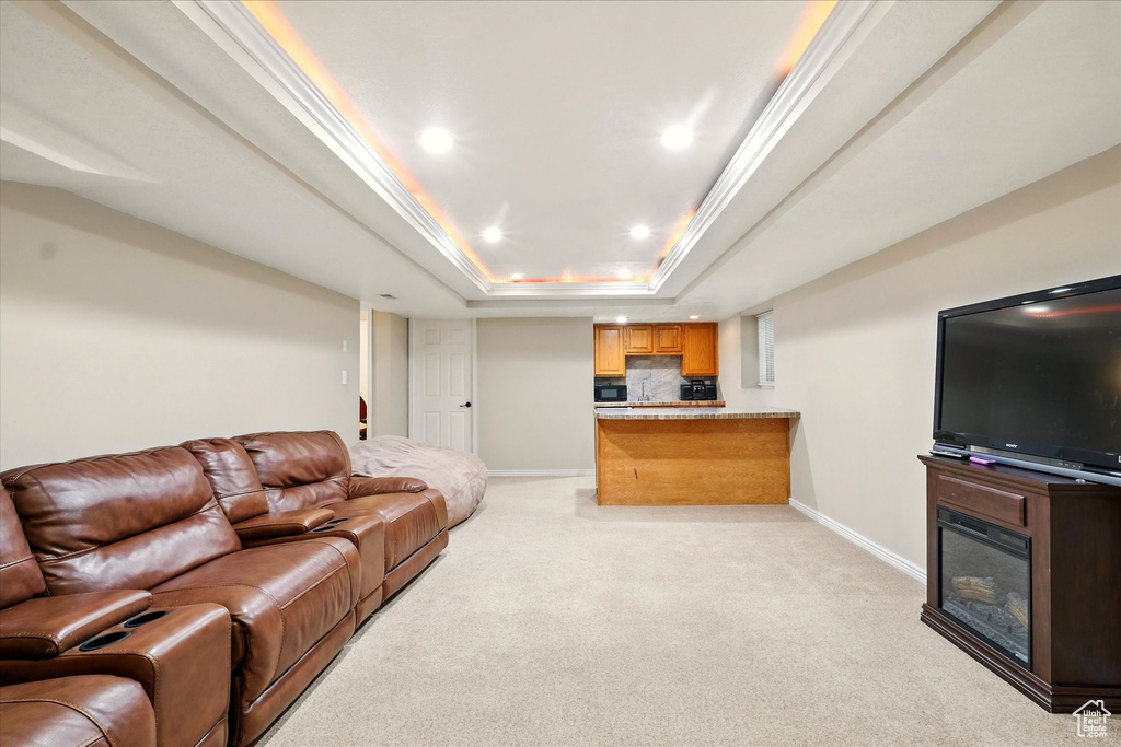 Living area with light colored carpet, a raised ceiling, recessed lighting, a glass covered fireplace, and bar