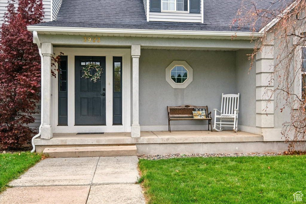 Property entrance featuring a shingled roof and a porch