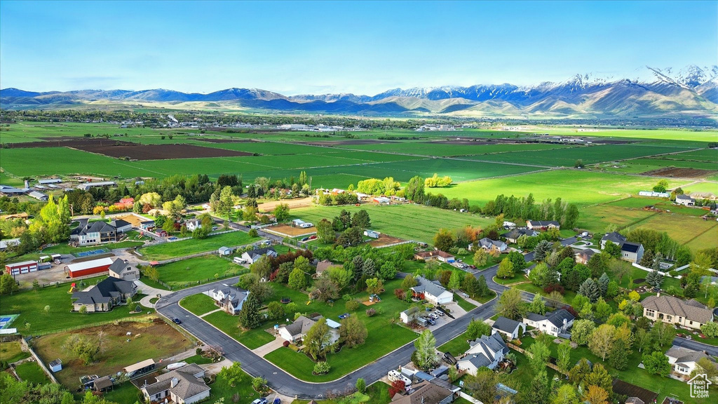 Aerial view of sparsely populated area with a mountain backdrop and rows of crops