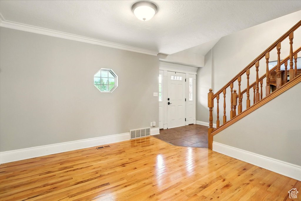 Entrance foyer featuring stairway, wood finished floors, and ornamental molding