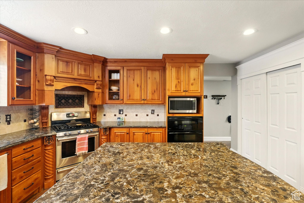 Kitchen featuring stainless steel appliances, tasteful backsplash, brown cabinets, glass insert cabinets, and recessed lighting