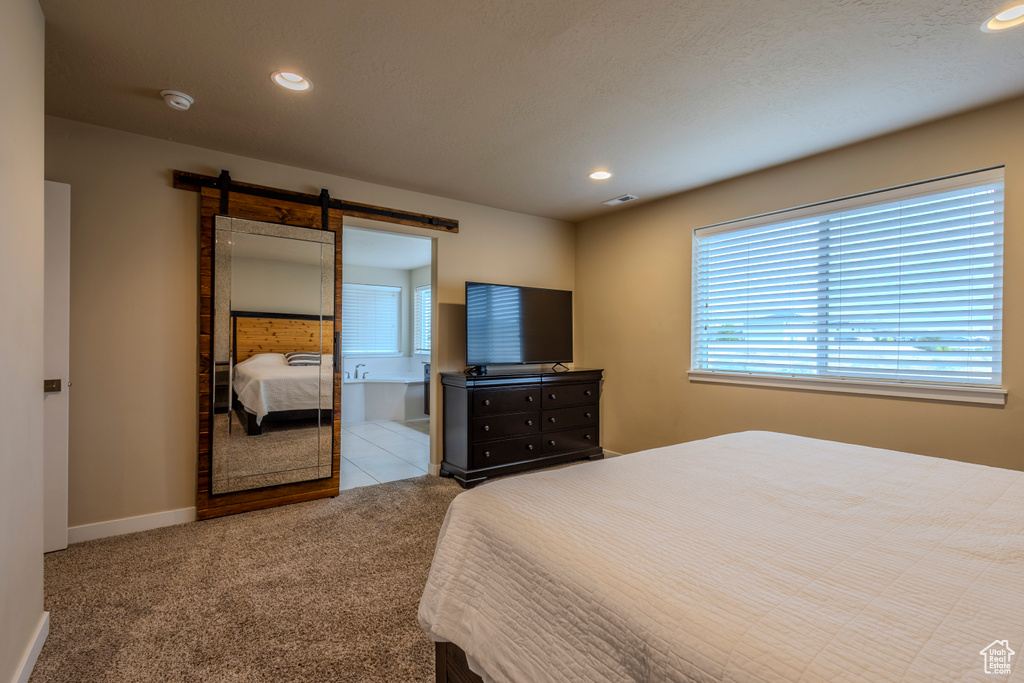 Carpeted bedroom featuring a barn door and recessed lighting