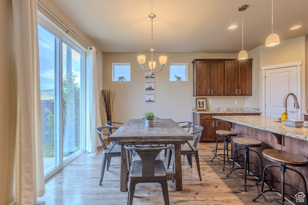 Dining room with light wood finished floors, a chandelier, and recessed lighting