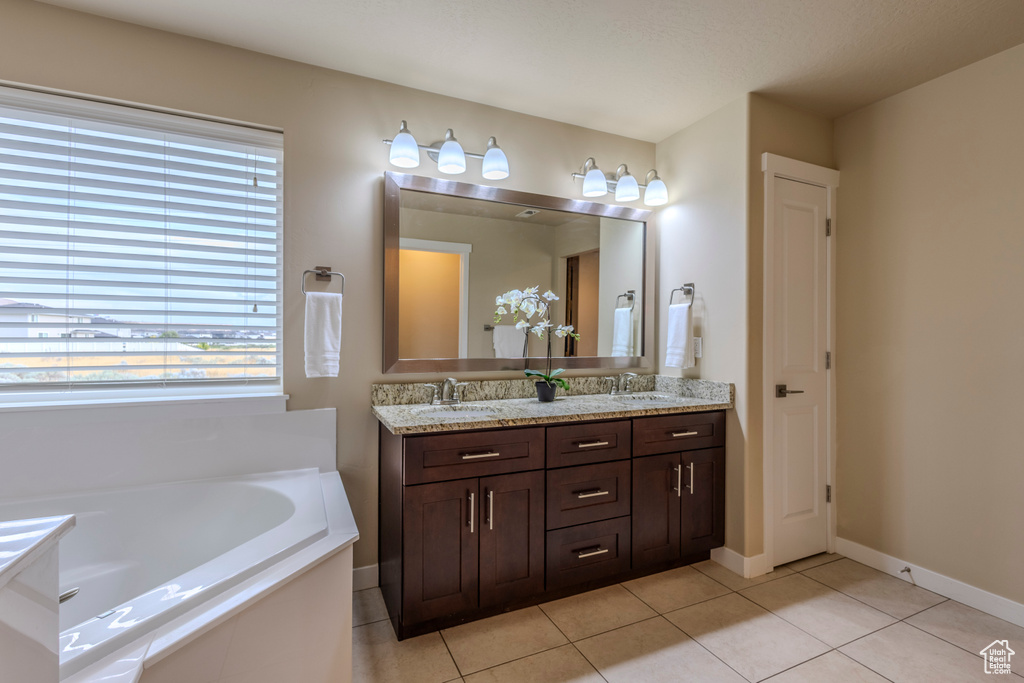 Bathroom with double vanity, a garden tub, and tile patterned flooring