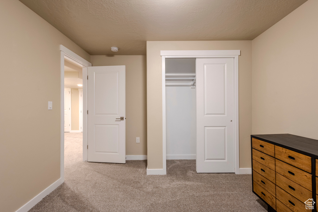 Unfurnished bedroom featuring carpet, a closet, and a textured ceiling
