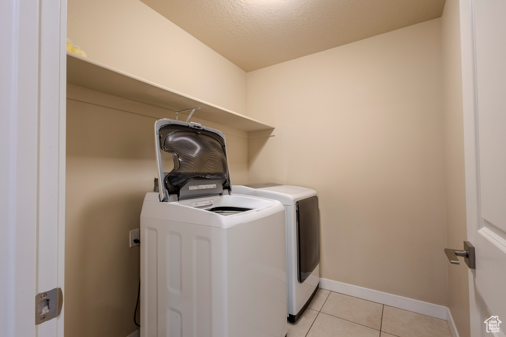 Laundry area with washer and dryer and light tile patterned flooring