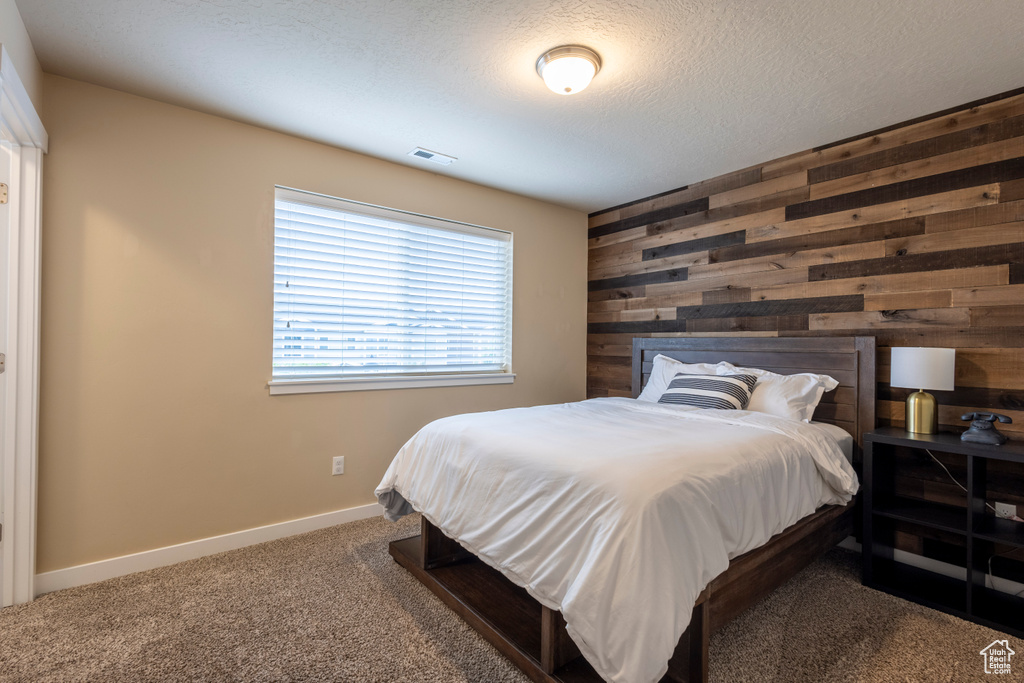 Carpeted bedroom with wooden walls and a textured ceiling