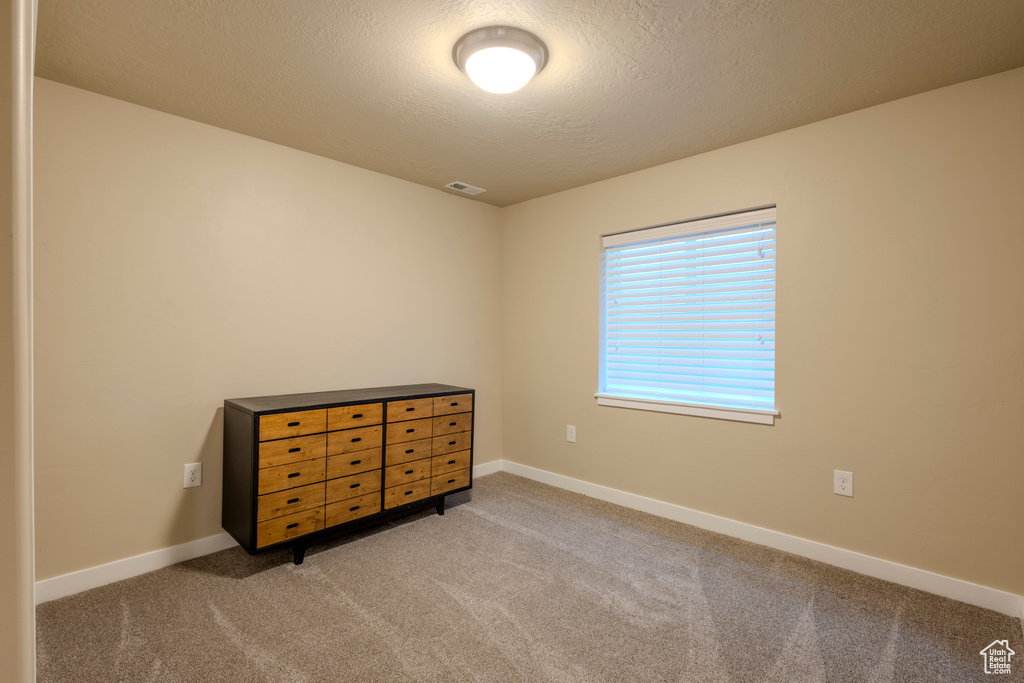 Carpeted bedroom with a textured ceiling and baseboards