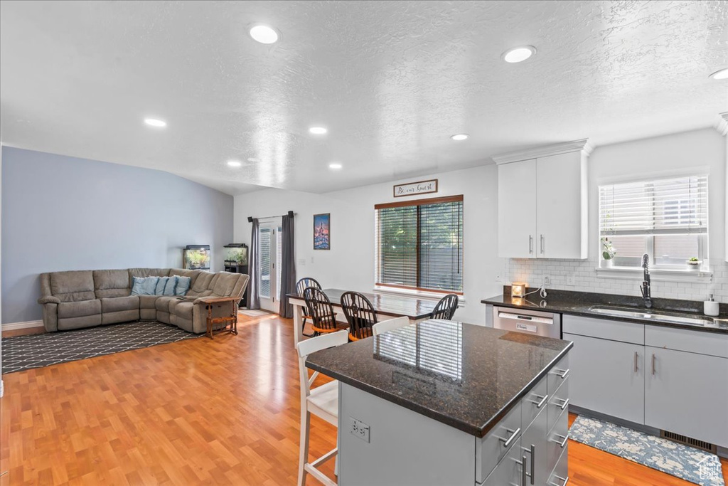 Kitchen featuring plenty of natural light, recessed lighting, a breakfast bar area, light wood-style floors, and a textured ceiling