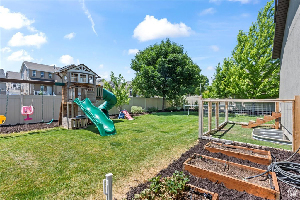 Fenced backyard featuring a garden and a playground